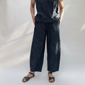 Person wearing dark denim pants and sandals on a white background