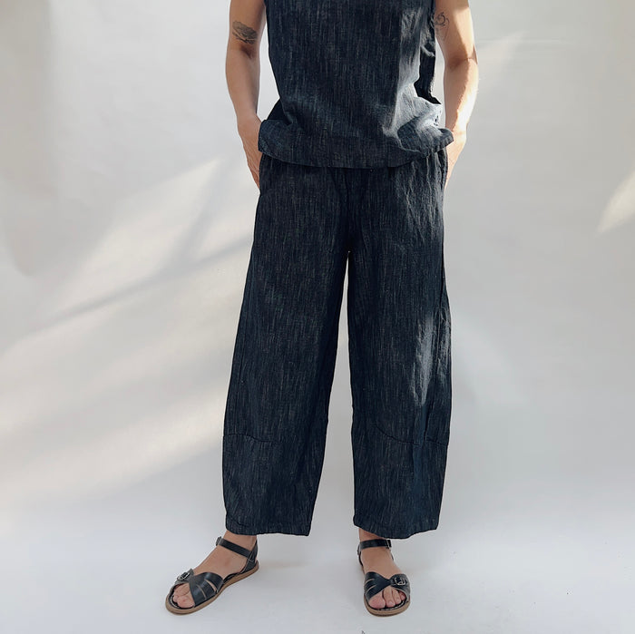 Person wearing dark denim pants and sandals on a white background