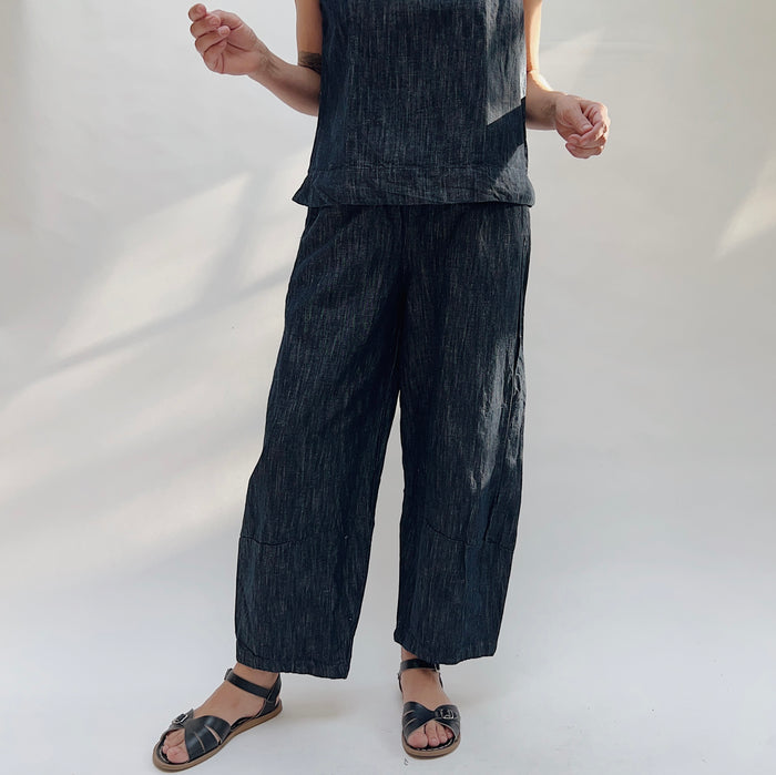 Person wearing a dark denim outfit with wide-leg pants on a white background