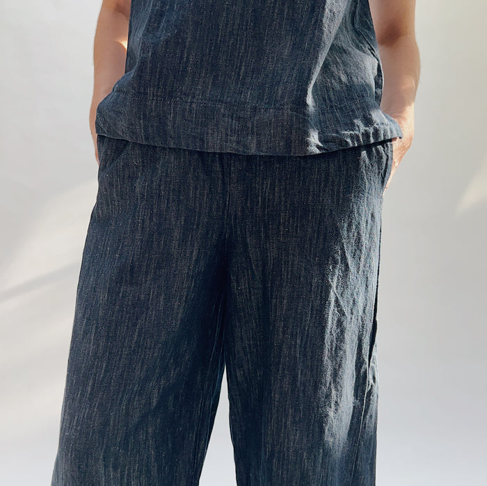 Close-up of a person wearing a dark denim outfit on a plain background