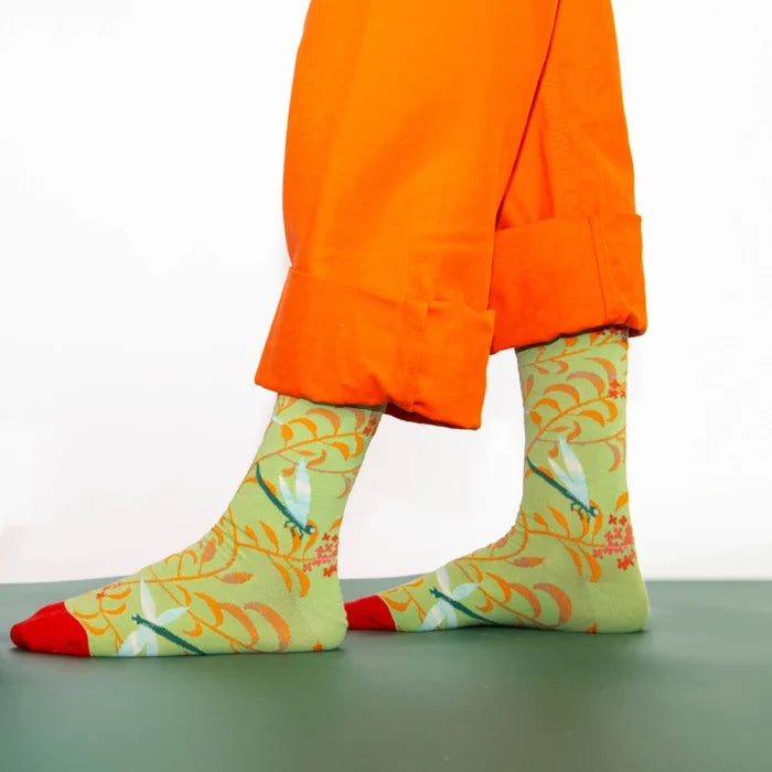 Person wearing colorful socks and orange pants standing on a green floor