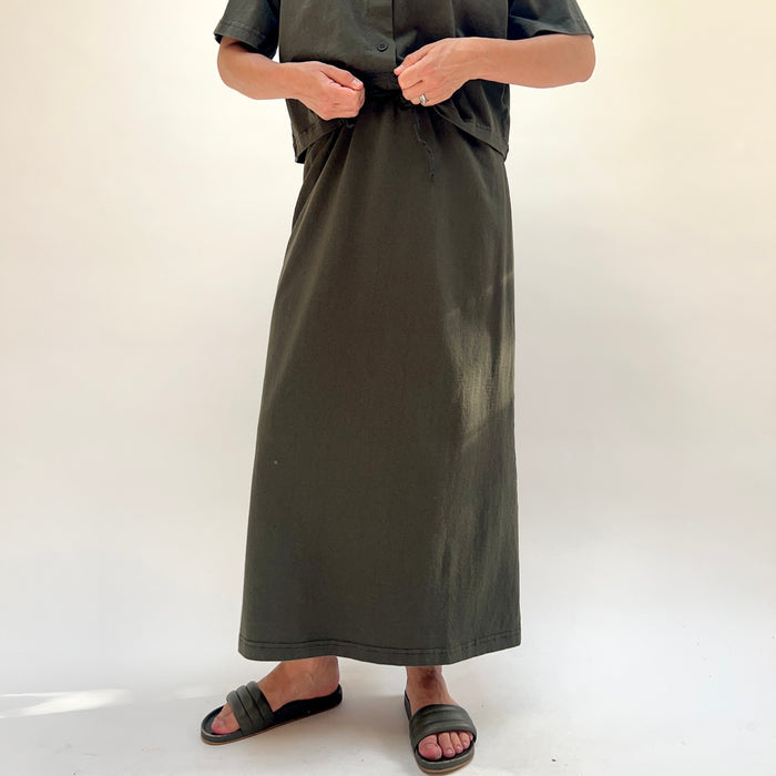 Person wearing a long dark green skirt on a white background