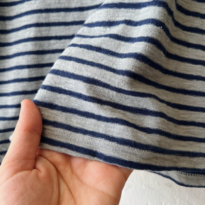 Close-up of a hand holding striped fabric with blue and gray horizontal lines.