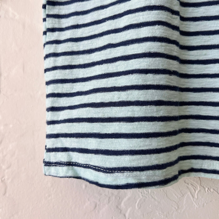 Close-up of striped fabric hem with blue and black horizontal lines on a textured beige background