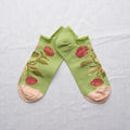 Green ankle socks with floral patterns on a light gray background