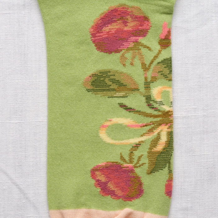 Close-up of green sock with floral pattern on a white background