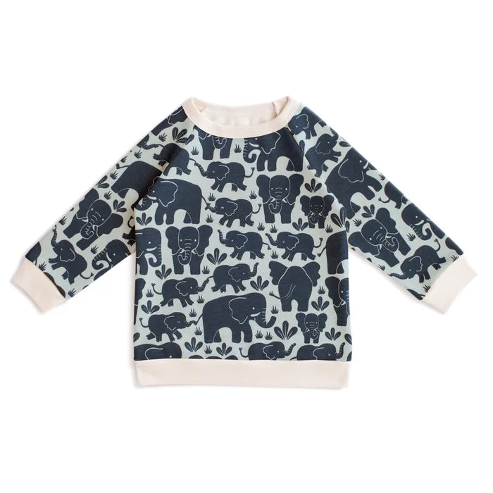 A long-sleeve baby sweatshirt featuring an all-over navy blue elephant pattern on a light sage green background, finished with solid cream ribbed cuffs, collar, and hem.