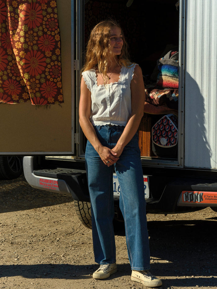 Woman standing in front of a truck with colorful items on a dirt road