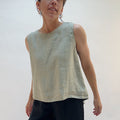 Person wearing a light green sleeveless top against a plain background