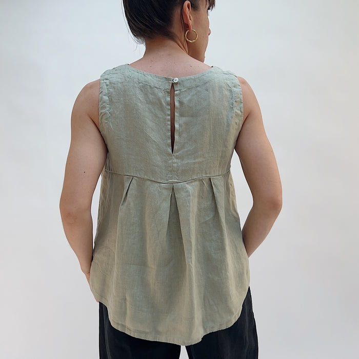 Person wearing a light green sleeveless top against a white background