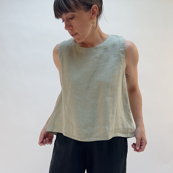 Person wearing a light green sleeveless top against a plain background