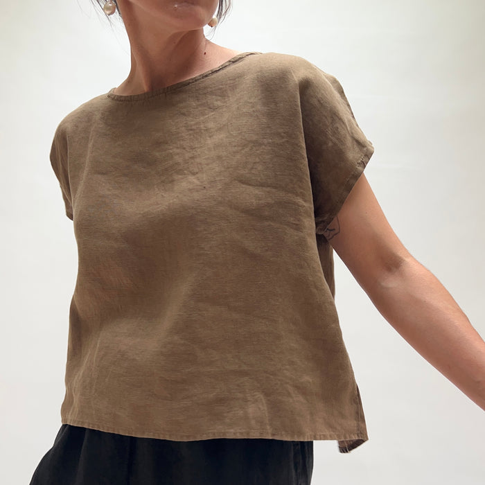 Person wearing a brown t-shirt against a white background