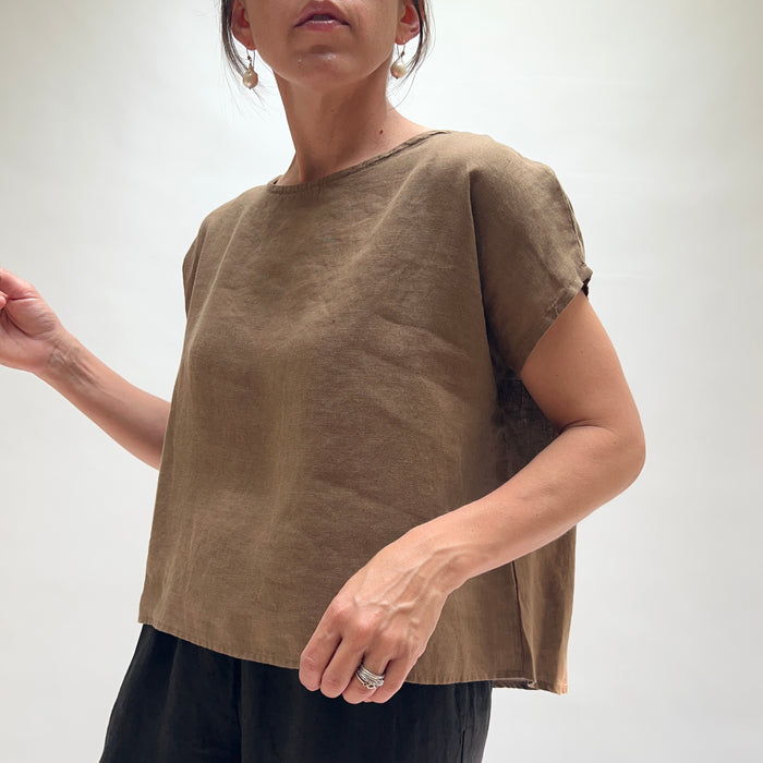 Person wearing a brown top and black pants on a white background