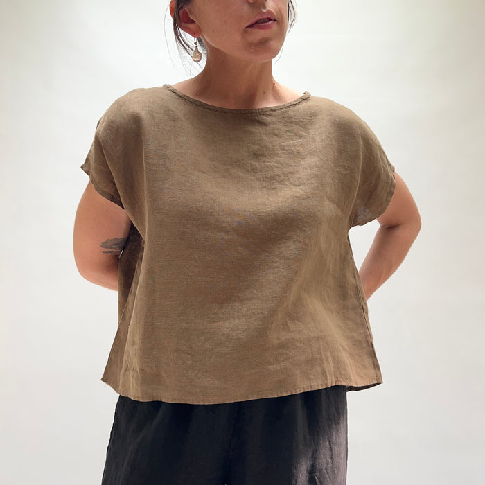 Person wearing a brown t-shirt and dark pants on a white background