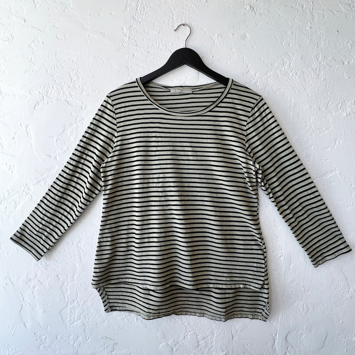 Green and black striped long-sleeve shirt on a hanger against a white wall