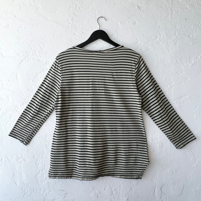 Green and black striped long-sleeve shirt on a hanger against a white wall