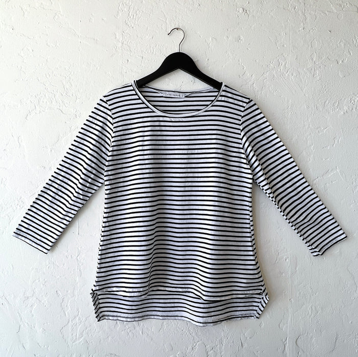 Black and white striped long-sleeve shirt on a hanger against a white wall