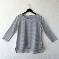Black and white striped long-sleeve shirt on a hanger against a white wall