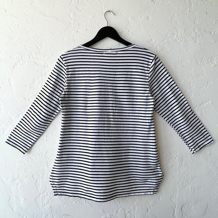 Black and white striped shirt on a hanger against a white wall as viewed from the back