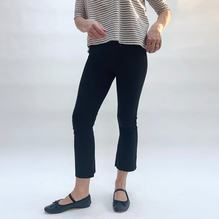 Person wearing black pants and a striped shirt on a white background