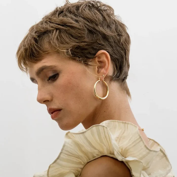 Close-up of a person wearing large gold hoop earring