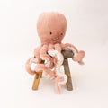 Jellycat Large Odell Octopus plush toy in blush pink, upright seated on a wooden stool showing a smiling face and eight dangling tentacles with cream sucker details on white background