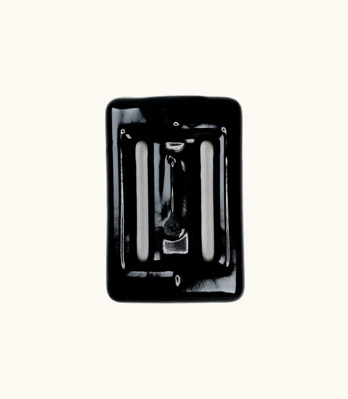 Black rubber-coated Lava Rock dive weight with slotted openings, photographed from above against a white background.