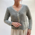 Person wearing a textured gray cardigan against a plain background