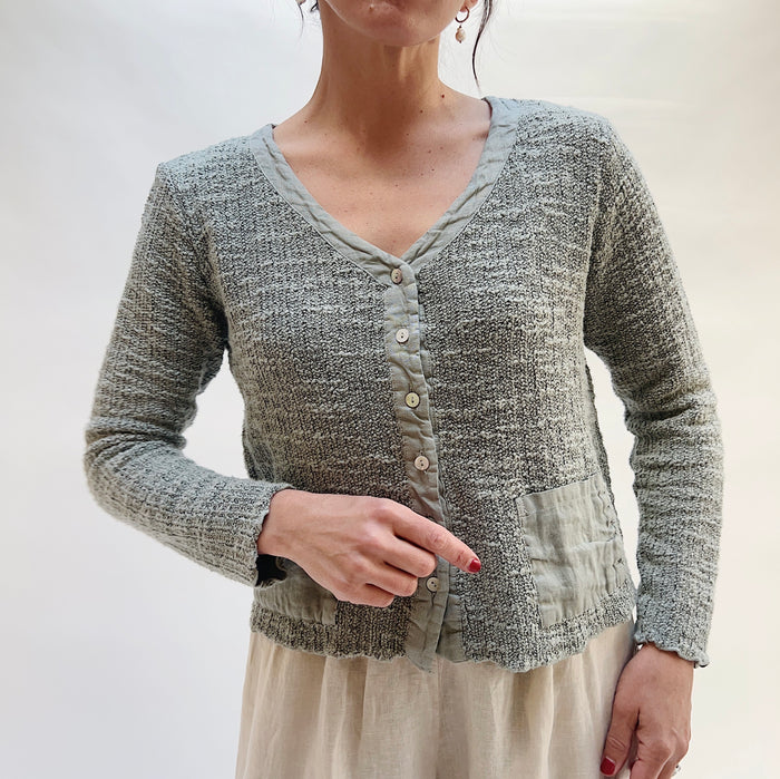Person wearing a textured gray cardigan against a plain background