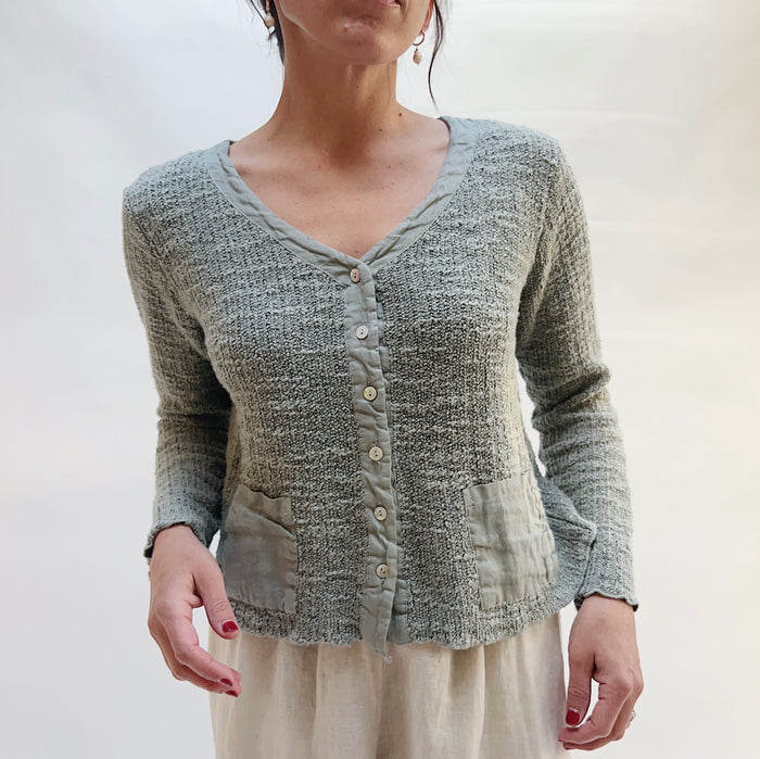 Person wearing a textured gray cardigan against a plain background