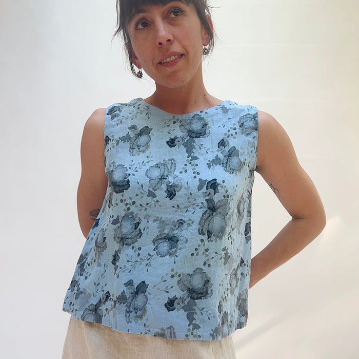 Woman wearing a sleeveless floral top against a plain background