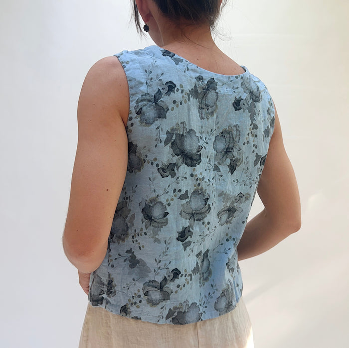 Person wearing a sleeveless top with floral pattern on a plain background