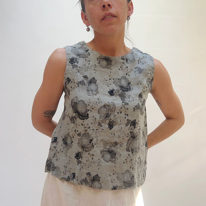 Person wearing a sleeveless floral top against a plain background
