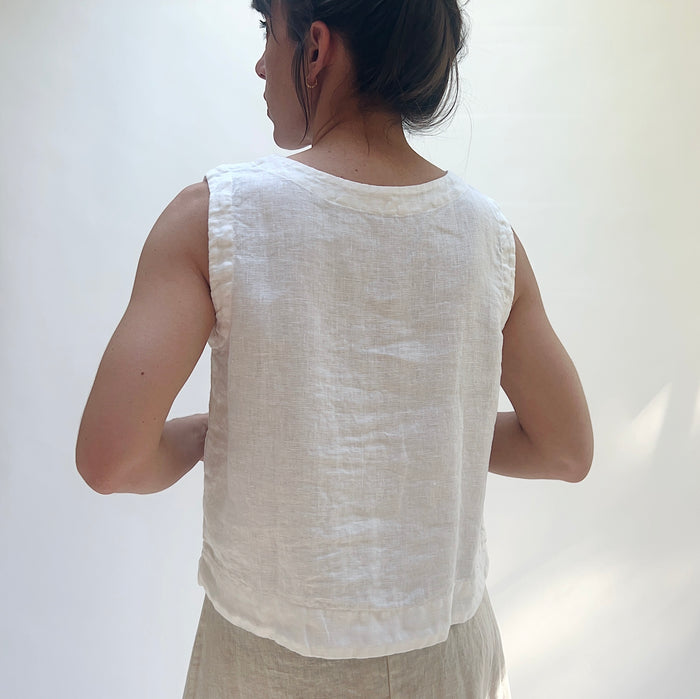 Person wearing a white sleeveless top against a plain background, viewed from behind