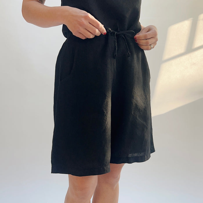 Person wearing black shorts against a plain background