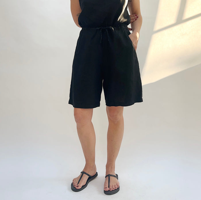 Person wearing a black sleeveless top and shorts on a white background