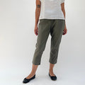 Front view of model wearing Cut Loose kelp olive linen-Tencel taper crop pant, showing elastic waistband, tapered leg, side seam detail, and cropped length