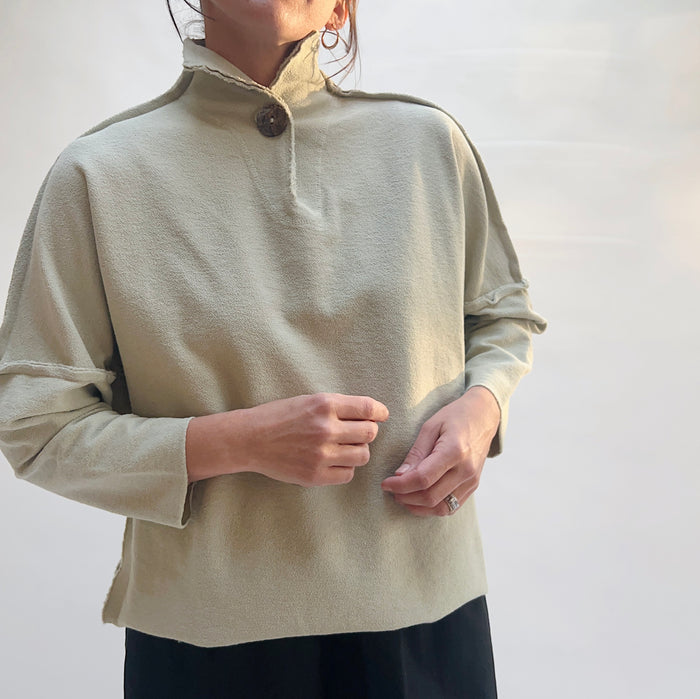 Close-up front view of Eleven Stitch Long Funnel Neck Slub Sweatshirt in Artichoke, showing funnel neckline, single button detail, and raw-edge seams