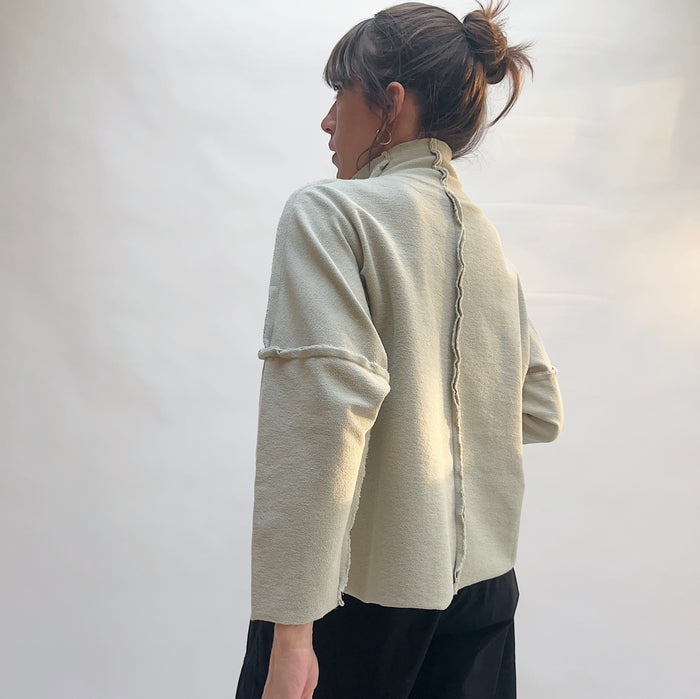 Back view of Eleven Stitch Long Funnel Neck Slub Sweatshirt in Artichoke, showing exposed center back seam and raw-edge sleeve detail