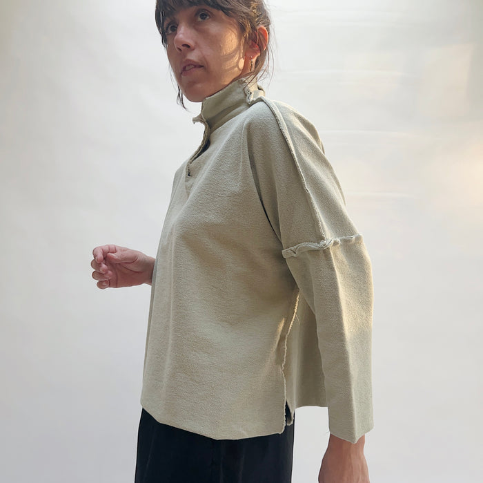 Side view of Eleven Stitch Long Funnel Neck Slub Sweatshirt in Artichoke, showing relaxed boxy silhouette, side slit hem, and raw-edge sleeve seam