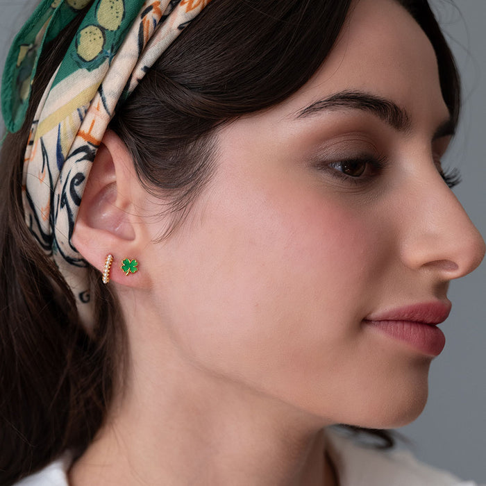 Close-up of a woman wearing green shamrock earrings with a patterned headband.