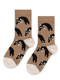 A pair of beige socks with a pattern of black cats in various poses.