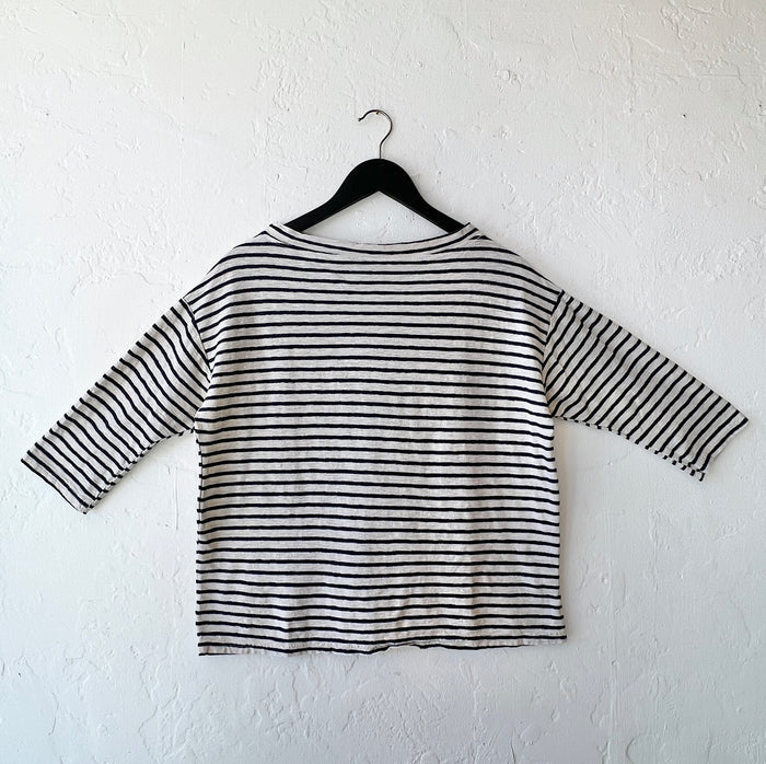 Navy and white striped shirt on a hanger against a white wall