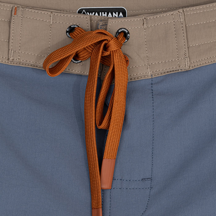 Close-up of the Waihana Offshore Blue Cruiser Board Shorts waistband, featuring a tan quilted waistband with branded eyelets and an orange flat drawstring tied at the front fly.