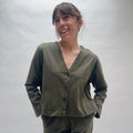 Woman wearing an olive green cardigan and pants against a plain background