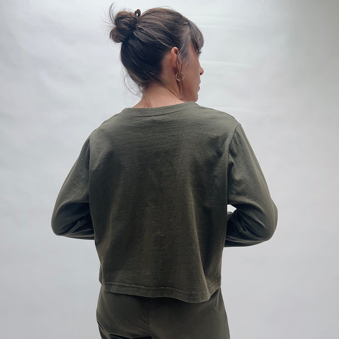 Person wearing an olive green cardigan against a plain background, viewed from the back