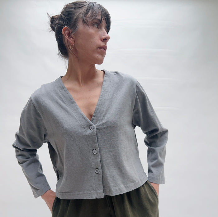 Woman wearing a gray cardigan against a plain background