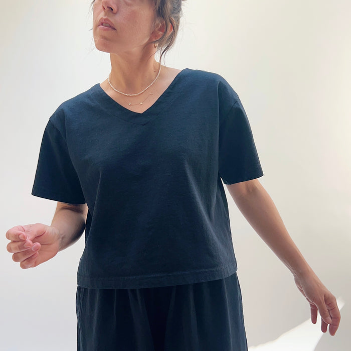 A person wearing a black crop V-neck t-shirt