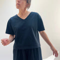 A person wearing a black crop V-neck t-shirt