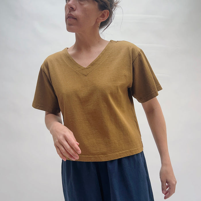 Person wearing a brown t-shirt against a plain background
